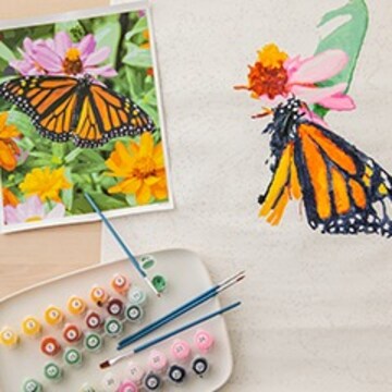 Picture of monarch butterfly and the start of a paint by numbers painting that mimics the picture. There are number paints also on the page